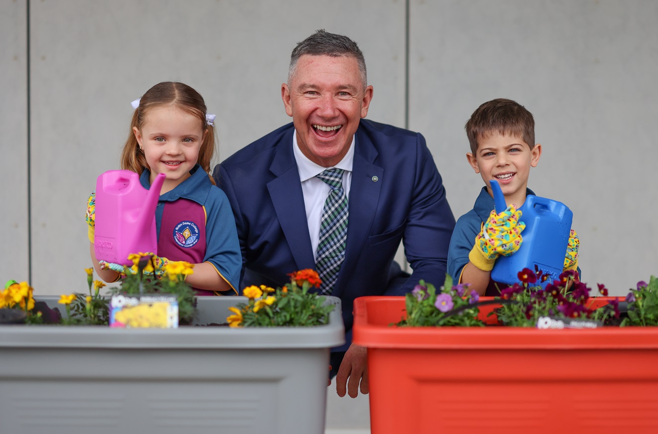 Principal Daniel McShea with students participating in a hands-on gardening activity, watering flowers in planter boxes