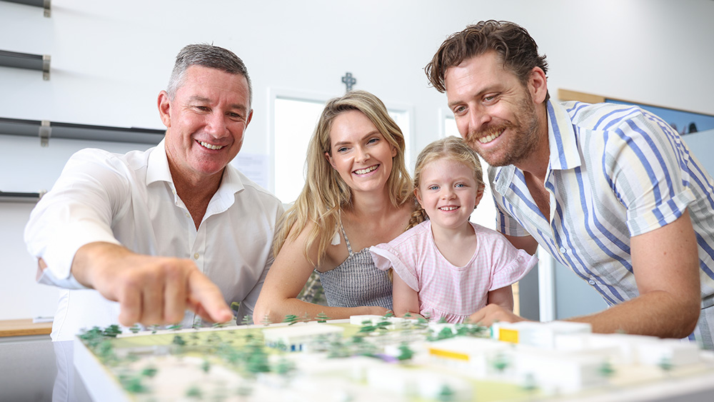 Principal and family of three gathered together to look at a 3D model of the future school